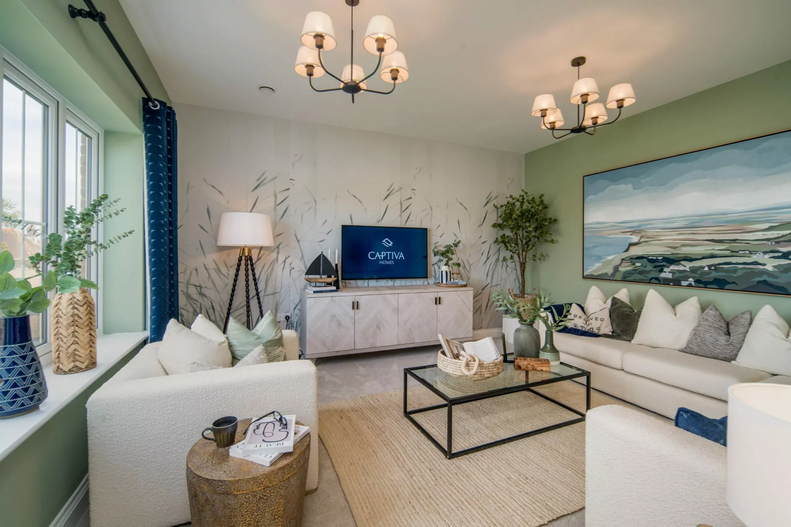 Modern living room with neutral sofas, green accent wall, landscape artwork, and a television displaying Captiva Homes l