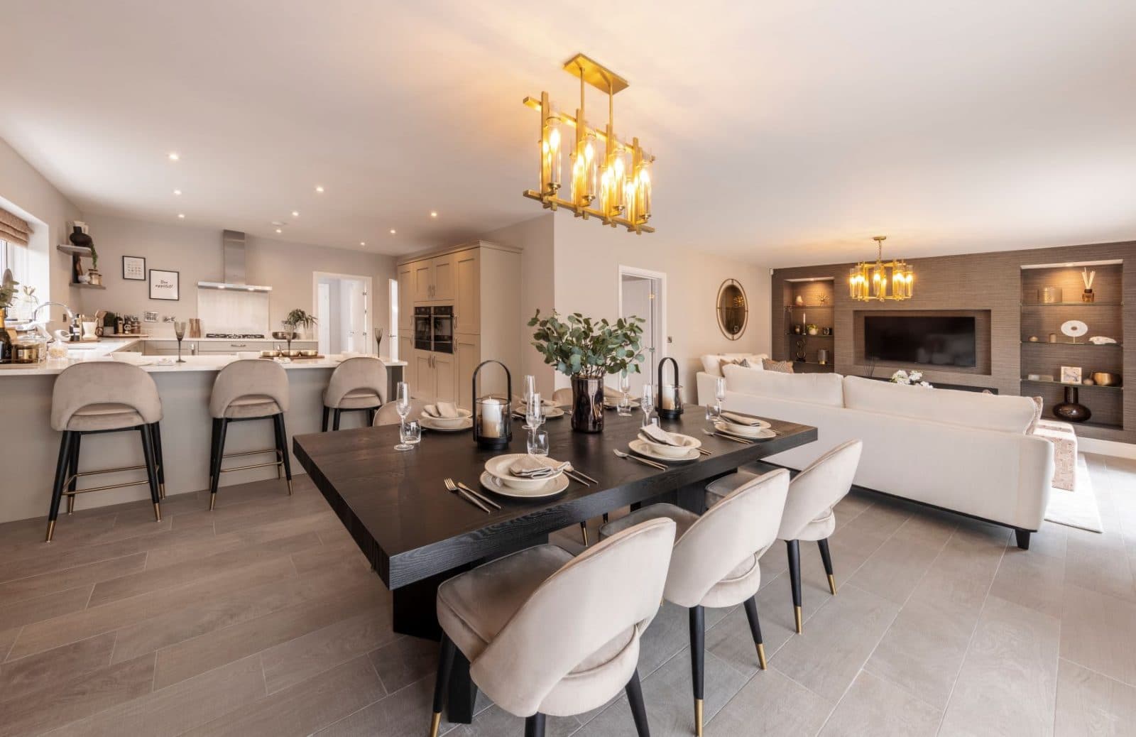Open-plan kitchen, dining area and living room with cream furnishings and a dark wood dining table at Queensbury Manor
