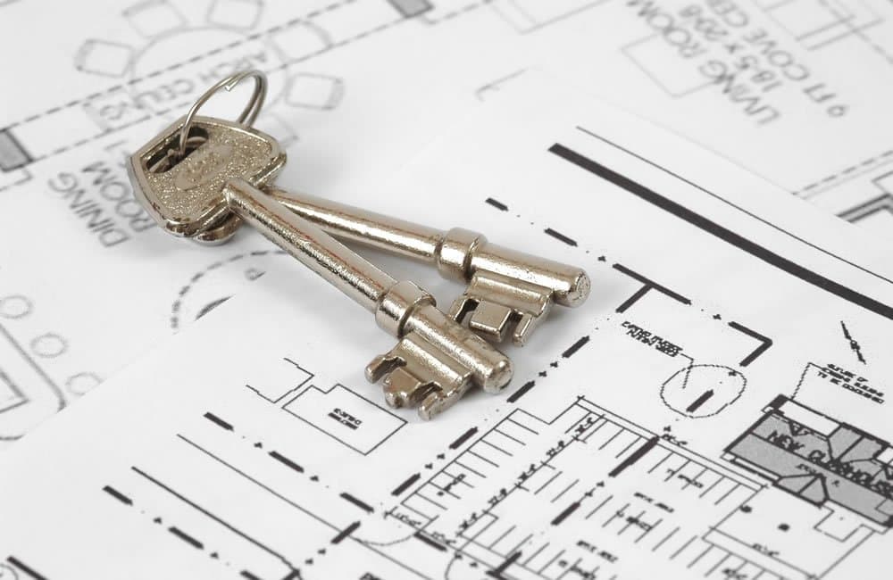 Two silver keys resting on a printed architectural floor plan for a new-build property