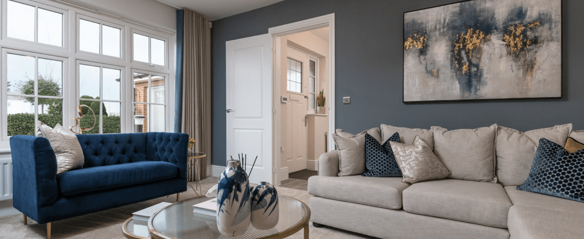Modern living room with a navy blue sofa, light grey corner sofa, abstract wall art, and coffee table in a new home